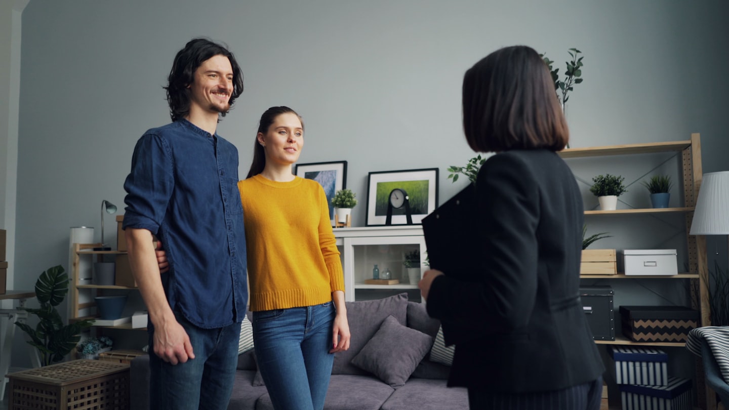 Immobilienmakler zeigt einem Paar ein unmöbliertes Haus.